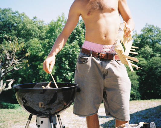 un mec allume un barbecue en caleçon rose