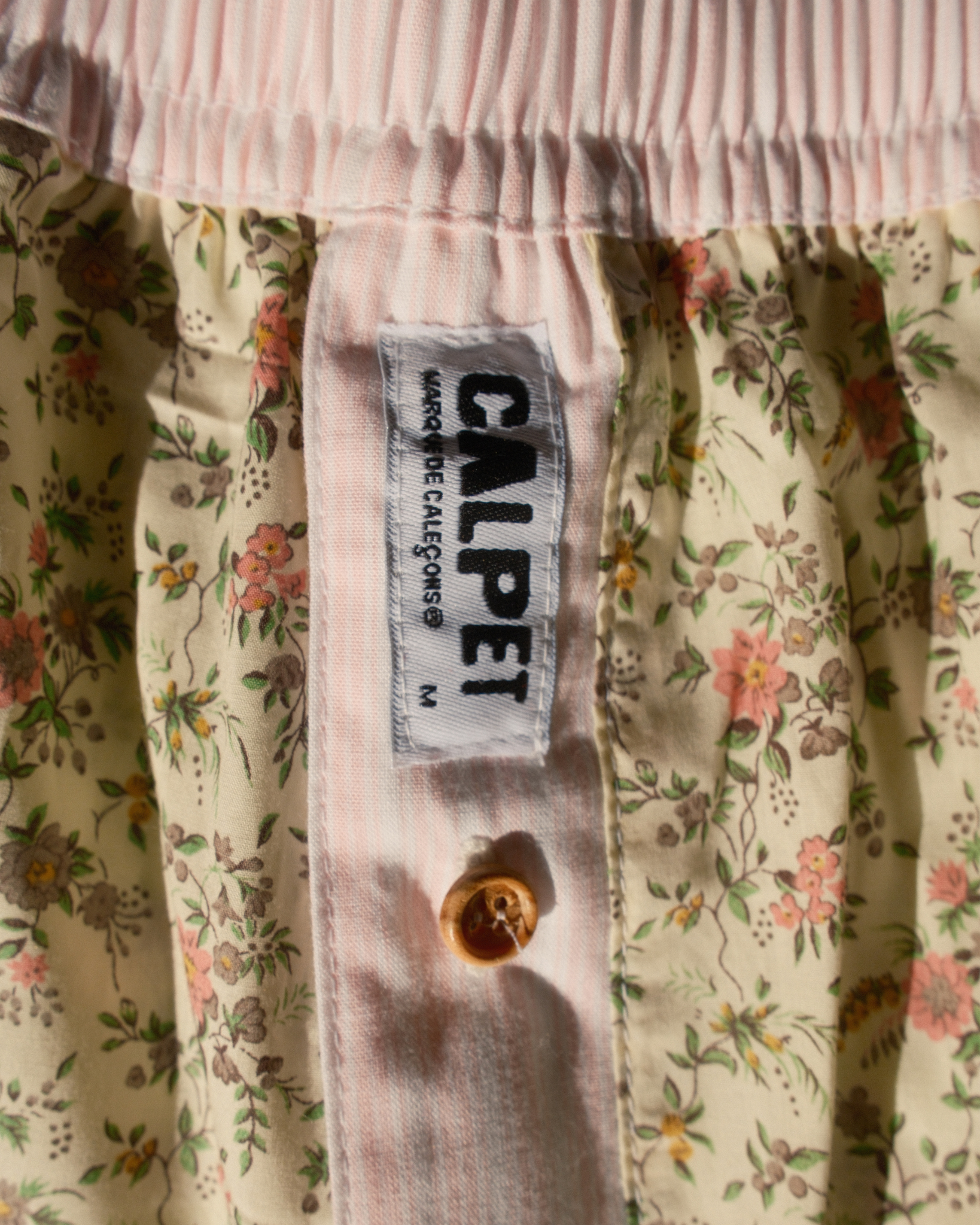 Gros plan sur la braguette rose pâle, le bouton en bois et l'étiquette CALPET du caleçon fleuri vintage