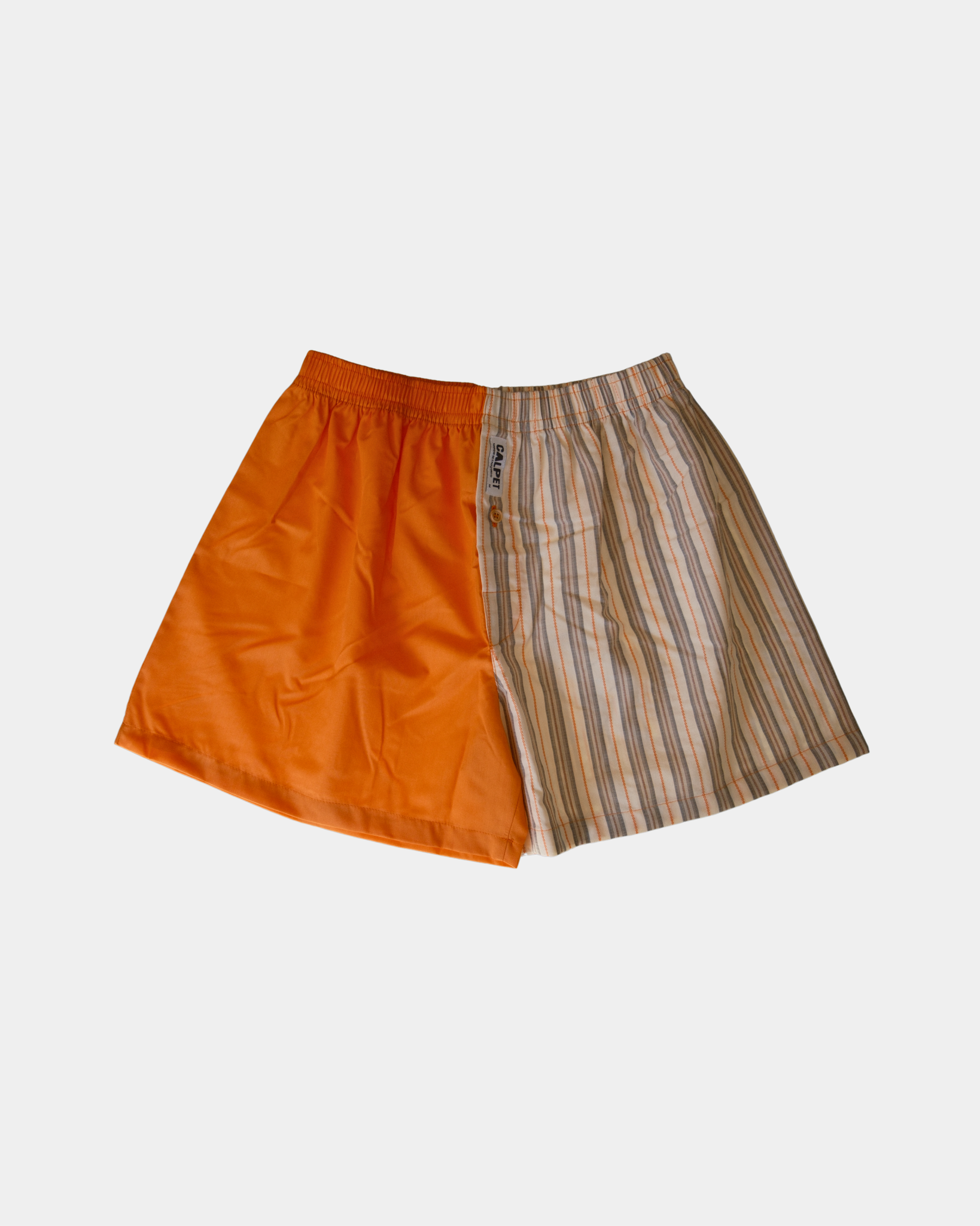 caleçon parachute dépareillé CALPET avec une jambe orange unie et une jambe à rayures orange, grises et beiges