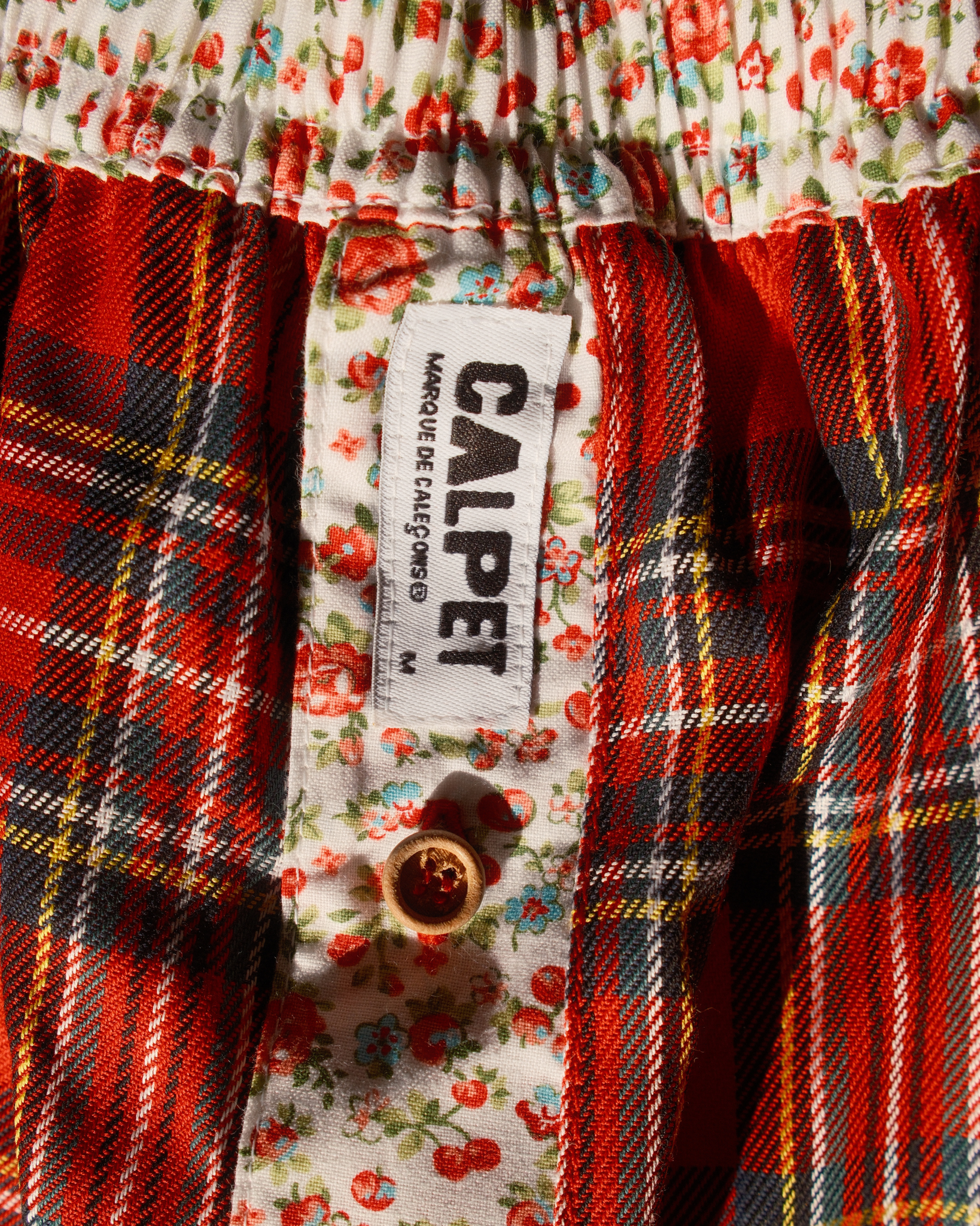 braguette à petites fleurs rouges et bleues, bouton en bois et étiquetteCALPET sur caleçon tartan rouge